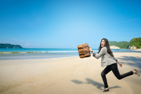 Cheerful asian businesswoman with briefcase going vacation to the beach. Free from workの写真素材