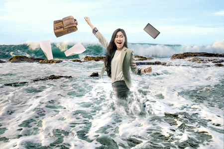 Pretty asian business woman throwing her work device and taking vacation on the beach. Free from workの写真素材