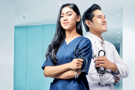 Young asian medical staff standing back to back with holding stethoscope in hospitalの写真素材