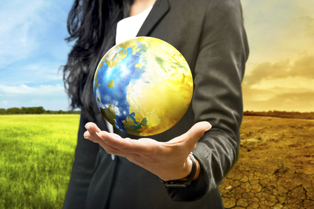 Business woman holding the earth against climate change background. Global awareness conceptの写真素材
