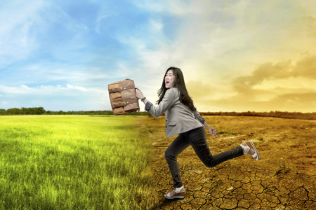 Beautiful asian business woman running with briefcase over climate change background. Global awareness conceptの写真素材