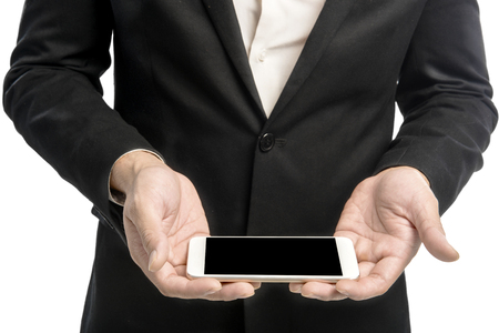 Businessman holding mobile phone on his hands standing isolated over white background. Black screen for copyspace areaの写真素材