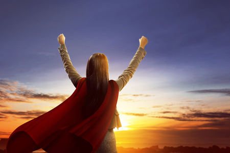 Rear view of asian super business woman with red cloak feel excited standing over sunset backgroundの写真素材