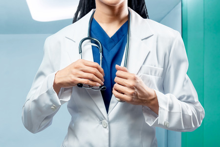 Doctor woman in white coat holding stethoscope in hospitalの写真素材