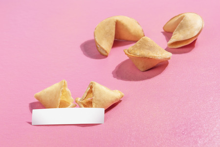 Broken fortune cookies with blank paper on the pink backgroundの写真素材