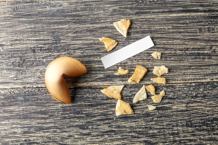 Cracked fortune cookies with blank paper on the wooden tableの写真素材