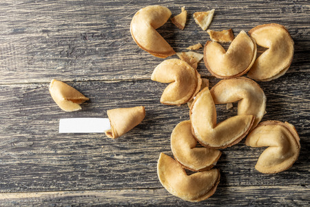 Cracked fortune cookies with blank paper on the wooden tableの写真素材