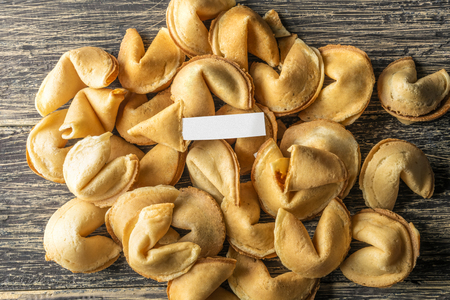 Pile of fortune cookies with blank paper on the wooden tableの写真素材