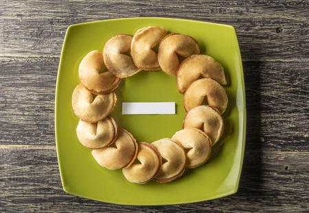 Fortune cookies with blank paper in the middle of green plate on wooden tableの写真素材