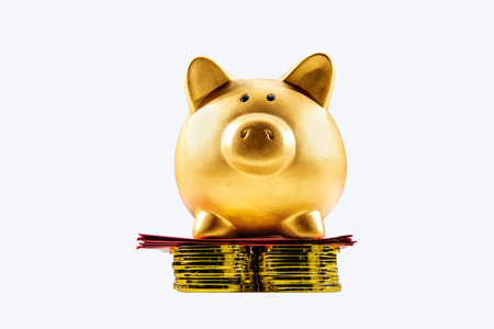 Piggy bank standing on the stack of golden coin and red envelopes isolated over white background. Chinese New Year. Year of the earth pigの写真素材