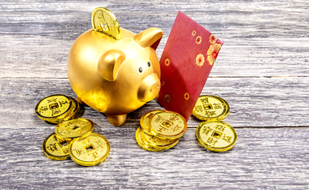 Piggy bank with golden coins and red envelopes on the wooden table. Chinese New Year. Year of the earth pigの写真素材