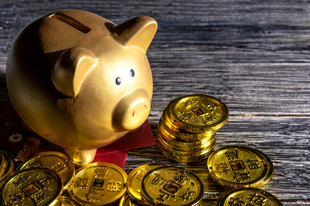 Piggy bank with golden coins and red envelopes on the wooden table. Chinese New Year. Year of the earth pigの写真素材