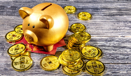 Piggy bank with golden coins and red envelopes on the wooden table. Chinese New Year. Year of the earth pigの写真素材