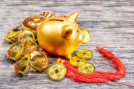 Piggy bank with golden coins and chinese ornament on the wooden table. Chinese New Year. Year of the earth pigの写真素材