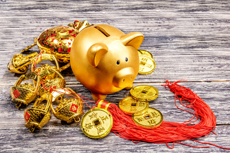 Piggy bank with golden coins and chinese ornament on the wooden table. Chinese New Year. Year of the earth pigの写真素材