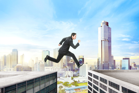 Handsome asian businessman jumping over building gap on the cityの写真素材