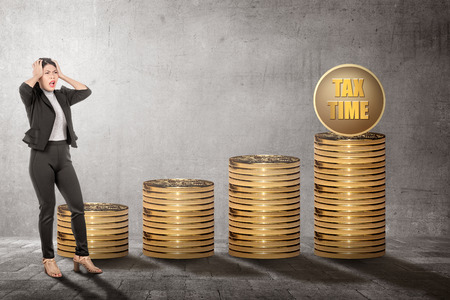Confused asian business woman with Tax time sign. Taxes conceptの写真素材