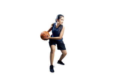 Young asian girl playing basketball isolated over white backgroundの写真素材