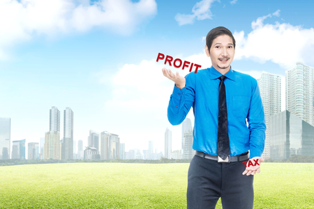 Handsome asian businessman showing unbalanced between profit and tax. Taxes conceptの写真素材
