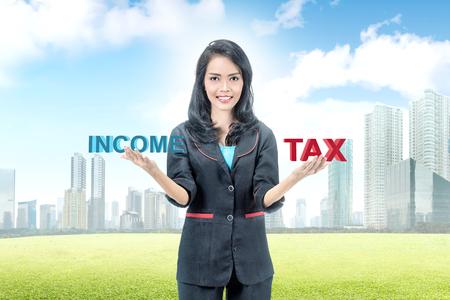 Young asian businesswoman balancing between income and tax. Taxes conceptの写真素材