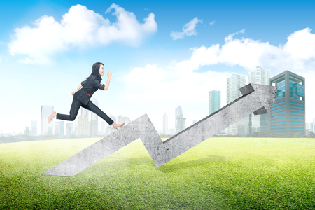 Happy asian business woman run on increased chart with city backgroundの写真素材