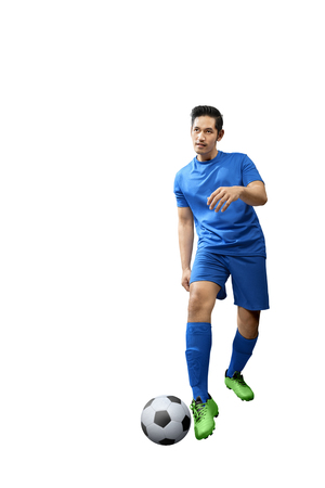 Young asian football player man with blue jersey in action posing isolated over white backgroundの写真素材