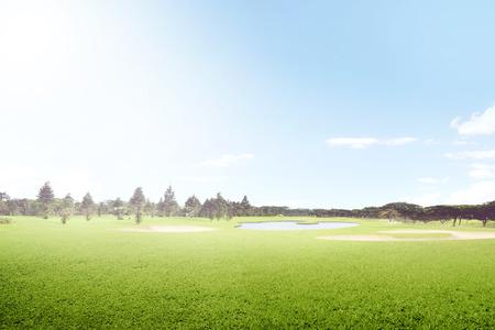 Beautiful golf course with sand bunkers and trees over blue sky backgroundの写真素材