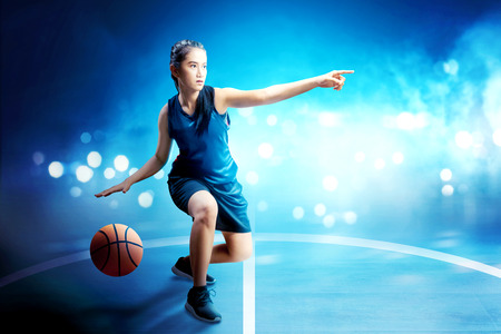 Beautiful asian woman in basketball uniform dribbling the ball on basketball courtの写真素材
