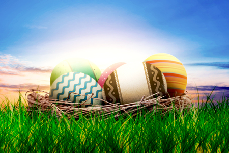 Colorful easter eggs in the nest on grass with sunset background. Happy Easterの写真素材