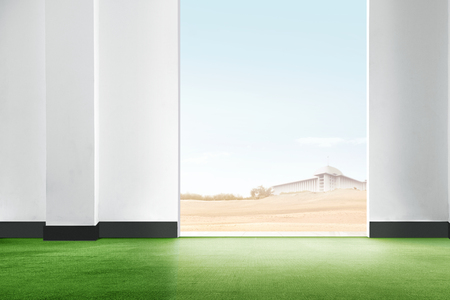 Interior of room with green carpet and open door with a view mosque on the desert against blue sky backgroundの写真素材