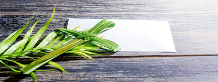 Closeup view of cross shape of palm leaf and palm branches with white blank paper on wooden background. Palm Sunday conceptの写真素材
