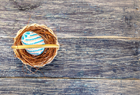 Colorful easter egg on the nest in wooden basket on wooden table. Happy Easterの写真素材