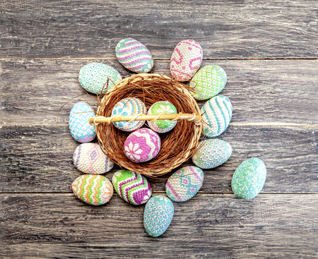 Colorful easter eggs on the nest in wooden basket and a wooden table. Happy Easterの写真素材