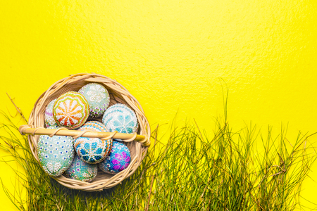 Colorful easter eggs on the wooden basket with grass on yellow background. Happy Easterの写真素材
