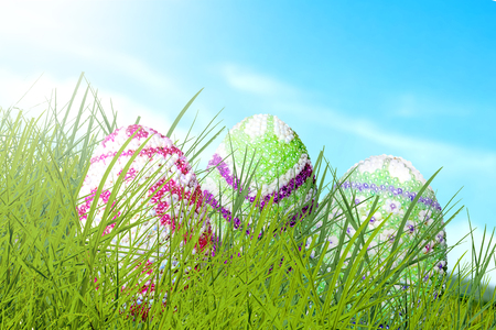 Colorful easter eggs hidden on the green grass with blue sky background. Happy Easterの写真素材