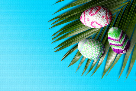 Close up view of Colorful easter eggs on the green palm leaf with blue color background. Happy Easterの写真素材
