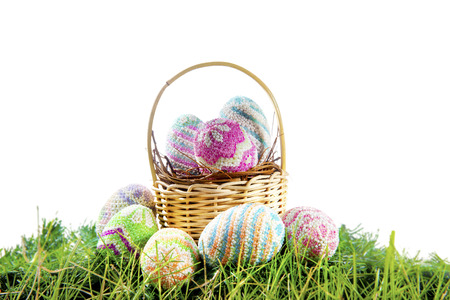 Colorful easter eggs on the nest in wooden basket and green grass over white background. Happy Easterの写真素材