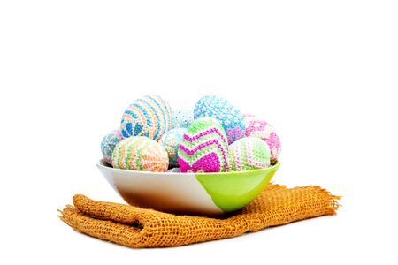 Colorful easter eggs on the bowl with fabric mat isolated over white background. Happy Easterの写真素材