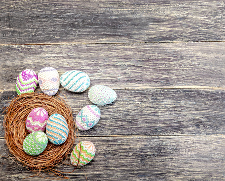 Colorful easter eggs in the nest and a wooden table. Happy Easterの写真素材