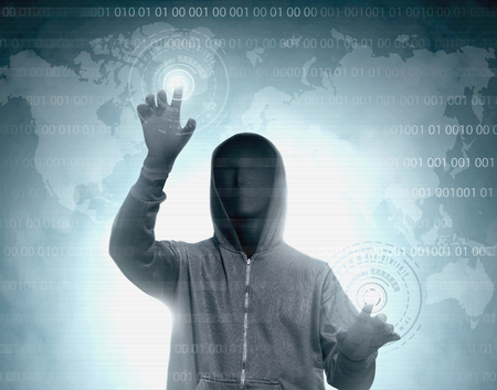 Hacker in black hoodie touching virtual screen with binary code and world map backgroundの写真素材