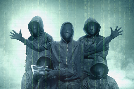 Hacker groups in black hoodie standing with binary code on virtual screen over green backgroundの写真素材