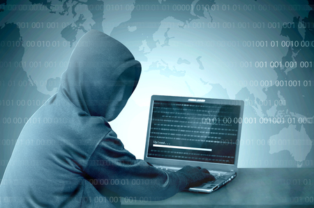Hacker in black hoodie using laptop on the desk to hacking system with binary code and upload the malware with world map backgroundの写真素材
