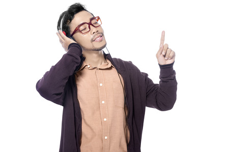 Happy asian man in brown jacket listening music with headphones on his head and enjoy the song isolated over white backgroundの写真素材