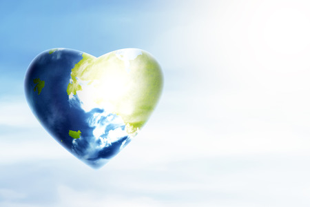 Earth planet with heart shape over blue sky background. Earth hour conceptの写真素材