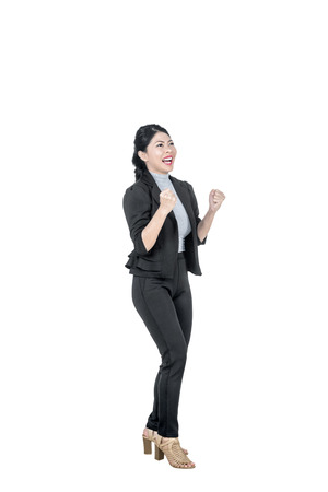 Excited asian business woman raise hands celebrates success posing isolated over white backgroundの写真素材