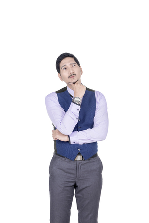 Portrait of asian businessman thinking something posing isolated over white backgroundの写真素材