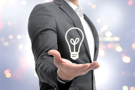 Businessman showing bright light bulb in the hands as a symbol of innovative idea. Business conceptの写真素材