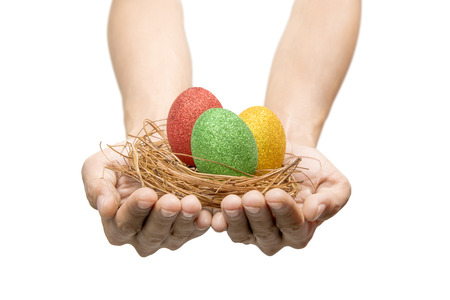 Human hands holding nest with colorful easter eggs isolated over white background. Happy Easterの写真素材