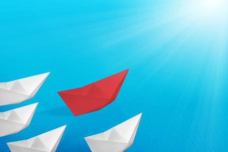 Red paper boats lead the white paper boats on the sea. Leadership conceptの写真素材