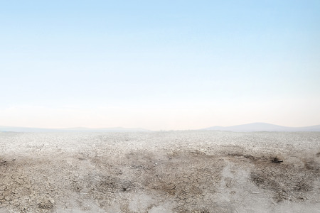 Soil drought on the field with smoke over blue sky backgroundの写真素材